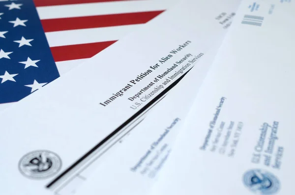 I-140 Іммігрантська петиція для іноземних робітників лежить на прапорі Сполучених Штатів з конвертом від Департаменту національної безпеки — стокове фото