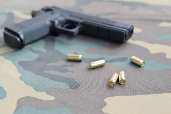 9 mm kule i pistolet leżą na kamuflażu zielony materiał. Zestaw przedmiotów strzelniczych lub zestaw samoobrony — Zdjęcie stockowe
