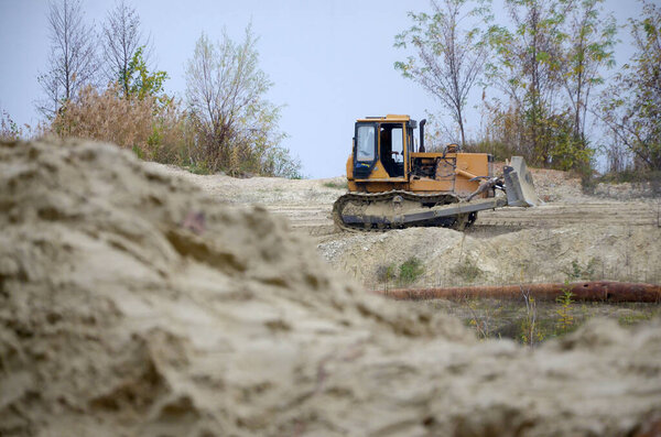 Quarry aggregate with heavy duty machinery. Caterpillar loader Excavator with backhoe driving to construction site quarry