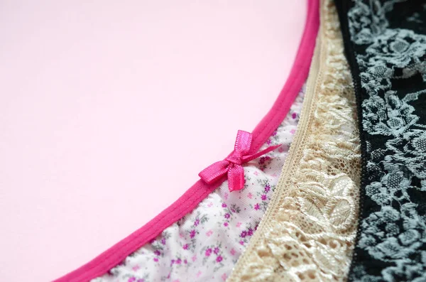 Bílé, černé a růžové dámské spodní prádlo s krajkou na růžovém pozadí s kopírovacím prostorem. Reklama na obchod krásné a pohodlné dámské spodní prádlo — Stock fotografie