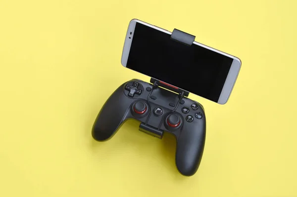 Gamepad preto moderno para smartphone no fundo amarelo. Dispositivo móvel de jogos de vídeo — Fotografia de Stock