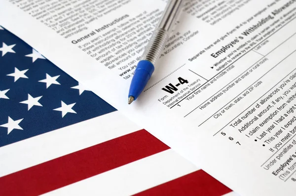 Formulaire W-4 Certificat de retenue d'indemnité d'employé et stylo bleu sur le drapeau des États-Unis. Formulaire fiscal des services fiscaux internes — Photo