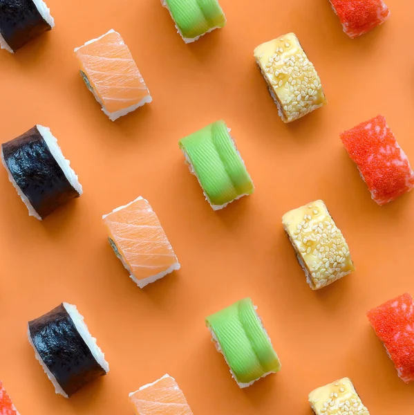 Diferentes tipos de rolos de sushi asiáticos no fundo laranja. Minimalismo vista superior plano leigos padrão com comida japonesa — Fotografia de Stock
