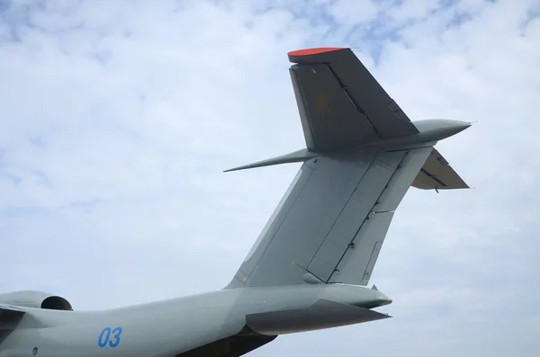 Big tail of armoured military aircraft close up against blue sky