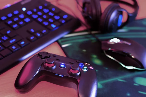 现代的游戏平台和游戏鼠标与键盘和耳机一起躺在黑暗的游戏室的桌子上。 在家里玩电子游戏的装置 — 图库照片