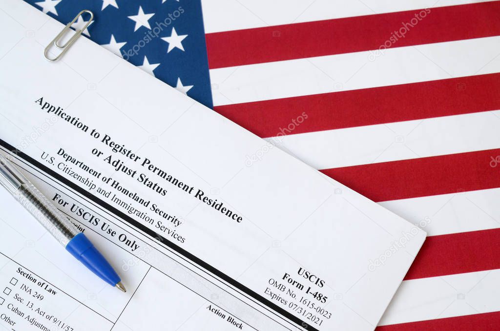 I-485 Application to register permanent residence or adjust status blank form lies on United States flag with blue pen from Department of Homeland Security
