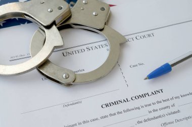 District Court Criminal complaint court papers with handcuffs and blue pen on United States flag clipart