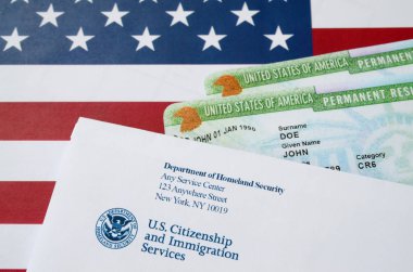 United States Permanent resident green cards from dv-lottery lies on United States flag with envelope from Department of Homeland Security clipart
