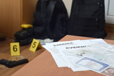 Evidence Labels and green card with ssn number lies on table with big amount of items as evidence in crime scene investigation process on backdrop clipart