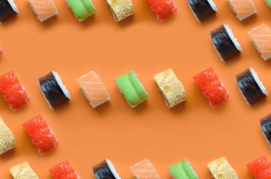 Turuncu arka planda farklı Asya suşi çeşitleri var. Minimalizm üst görünüm düz Japon yemekleri ile yatıyordu