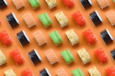 Turuncu arka planda farklı Asya suşi çeşitleri var. Minimalizm üst görünüm düz Japon yemekleri ile yatıyordu
