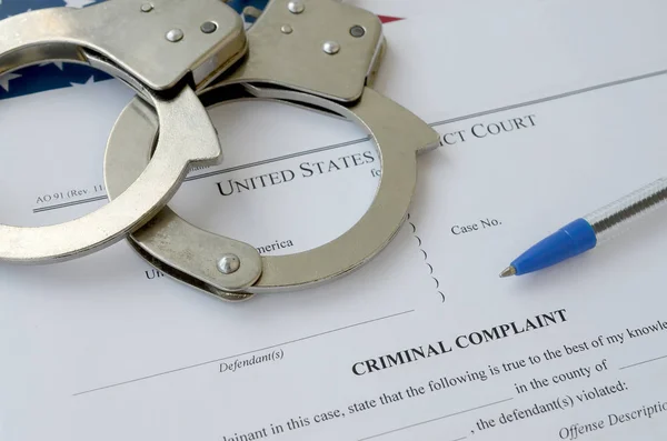 District Court Criminal complaint court papers with handcuffs and blue pen on United States flag — Stockfoto