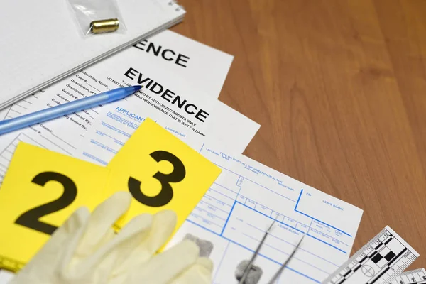 Paperwork during crime scene investigation process in csi laboratory. Evidence labels with fingerprint applicant and rubber gloves on vooden table — 스톡 사진