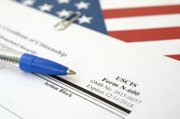 N-600 Application for Certificate of Citizenship blank form lies on the United States flag with blue pen from Department of Homeland Security — стокове фото