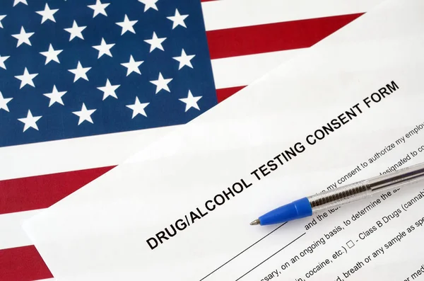 Drug and alcohol testing consent form with blue pen on United States flag — 스톡 사진