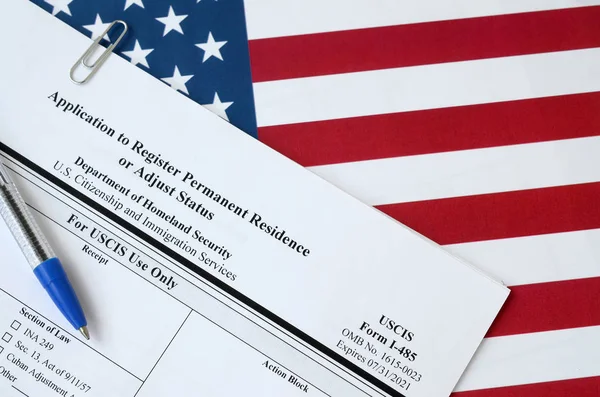 I-485永住権を登録するか、ステータスの空白のフォームを調整する申請は、国土安全保障省の青いペンで米国の国旗にあります — ストック写真