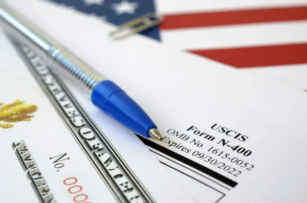 N-400 Antrag auf Einbürgerung und Einbürgerungsurkunde liegt auf der Flagge der Vereinigten Staaten mit blauem Stift des Heimatschutzministeriums — Stockfoto