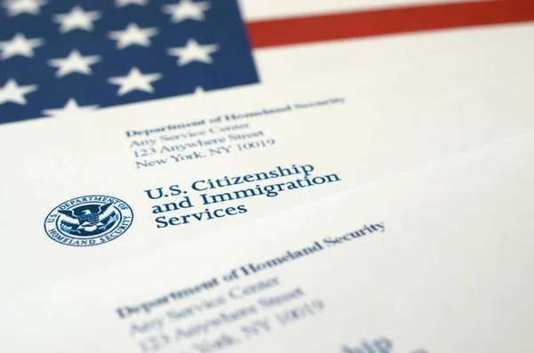 Конверты с письмом от USCIS на флаге США от Министерства внутренней безопасности — стоковое фото