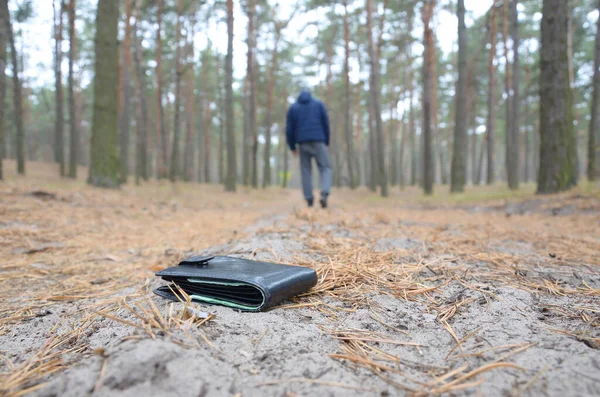 Young man loses his purse with euro money bills on Russian autumn fir wood path. Carelessness and losing wallet concept — Stock Photo, Image