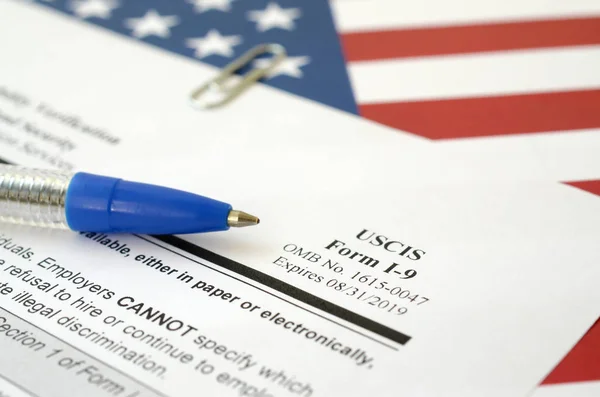 I-9 Employment Eligibility Verification blank form lies on United States flag with blue pen from Department of Homeland Security — 스톡 사진