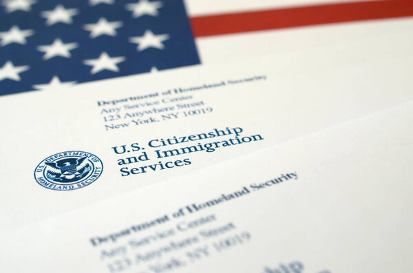 Конверты с письмом от USCIS на флаге США от Министерства внутренней безопасности
