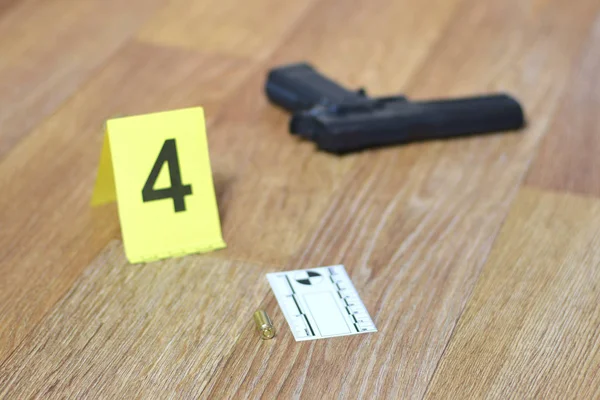 Concepto de investigación de la escena del crimen - Pistola y proyectil contra el marcador amarillo del crimen en el piso del apartamento —  Fotos de Stock