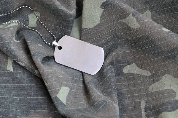 Silvery military beads with dog tag on camouflage fatigue uniform — Stock Photo, Image
