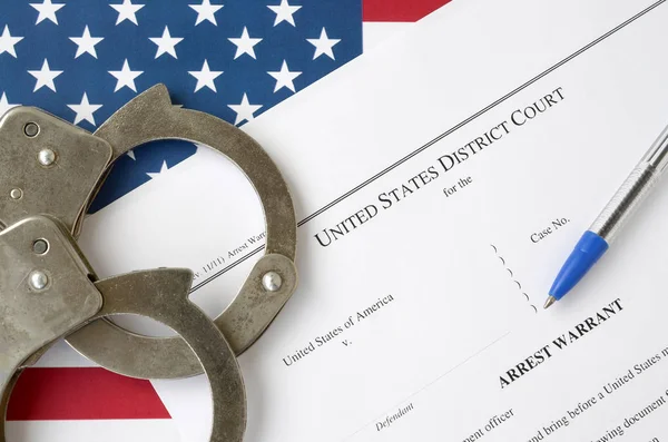 District Court Arrest Warrant court papers with handcuffs and blue pen on United States flag. Concept of permission to arrest suspect — Stockfoto