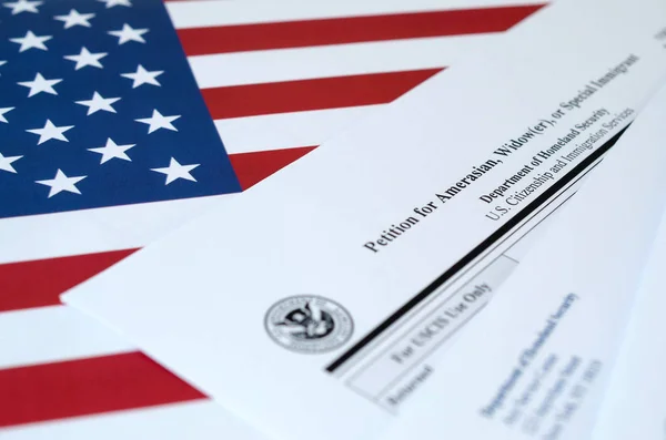 I-360アメリカ人、未亡人または特別移民のための請願書は、国土安全保障省の封筒付きの米国の旗にあります。 — ストック写真