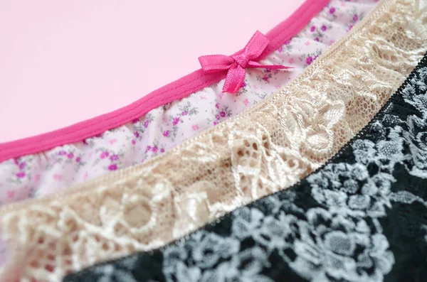 White, black and pink women underwear with lace on pink background with copy space. Advertising for shop of beautiful and comfortable women underwear