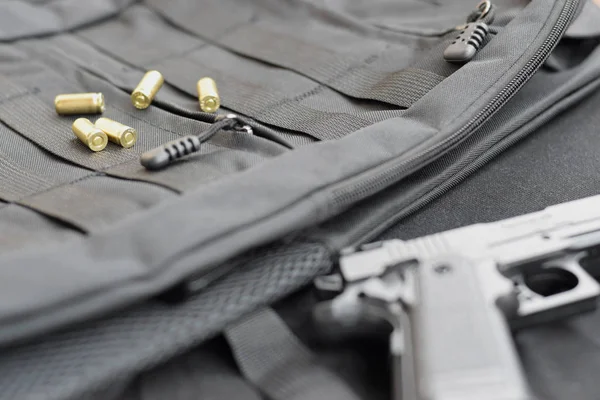 9 мм пули и пистолет лежат на черном тактическом рюкзаке — стоковое фото