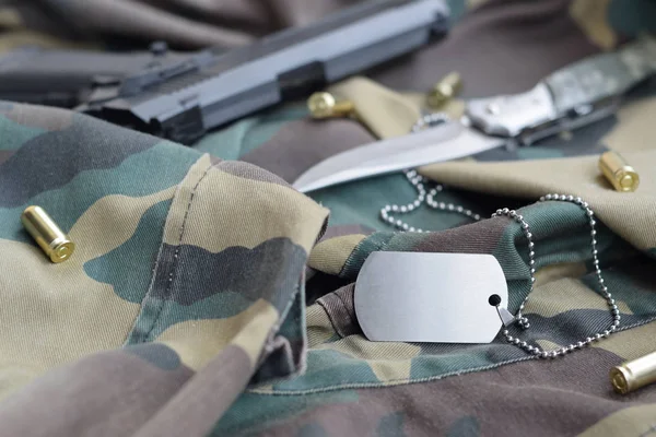 陸軍犬タグトークン9ミリメートル弾丸とピストル嘘に折り畳まれた迷彩緑の生地 — ストック写真