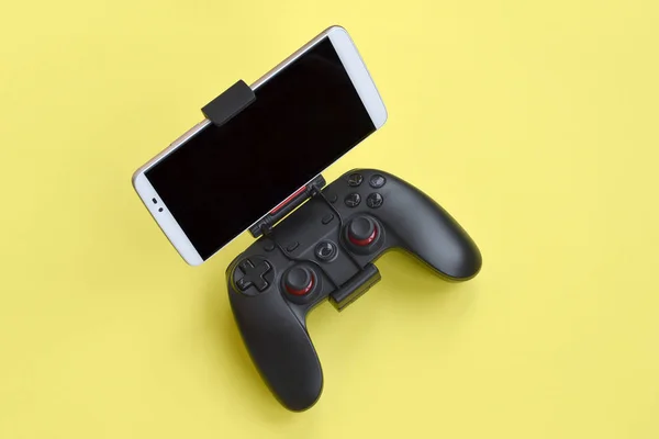 Moderno gamepad negro para smartphone sobre fondo amarillo. Dispositivo móvil de videojuegos —  Fotos de Stock
