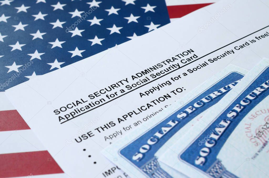 United States social security number cards lies on Application from social security administration on US flag