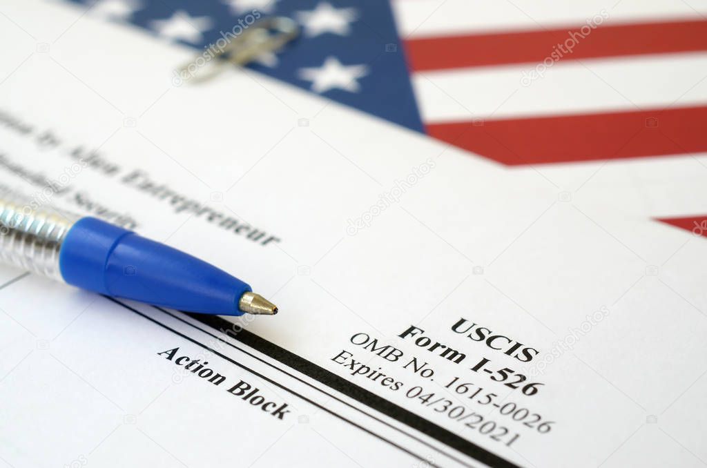 I-526 Immigrant Petition by Alien Entrepreneur blank form lies on United States flag with blue pen from Department of Homeland Security