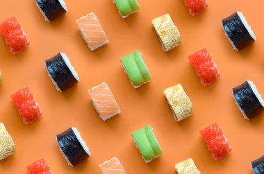 Turuncu arka planda farklı Asya suşi çeşitleri var. Minimalizm üst görünüm düz Japon yemekleri ile yatıyordu