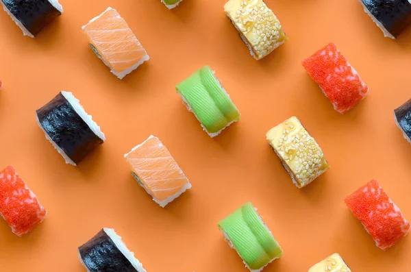 Diferentes tipos de rollos de sushi asiático sobre fondo naranja. Minimalismo vista superior plano laico patrón con comida japonesa —  Fotos de Stock