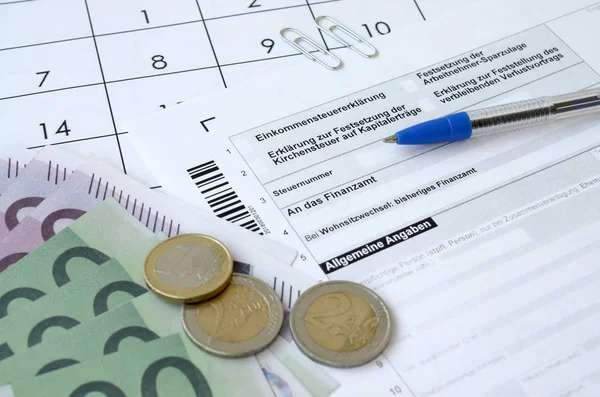 Formulario de impuestos alemán con bolígrafo y billetes de dinero europeo se encuentra en el calendario de la oficina. Contribuyentes en Alemania que utilizan la moneda del euro para pagar impuestos — Foto de Stock