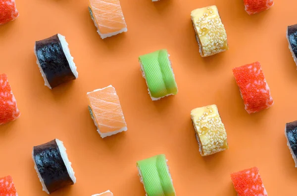 Diferentes tipos de rollos de sushi asiático sobre fondo naranja. Minimalismo vista superior plano laico patrón con comida japonesa —  Fotos de Stock