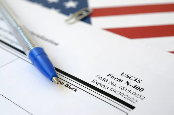N-400帰化の申請書は、国土安全保障省の青いペンで米国の旗にあります。 — ストック写真