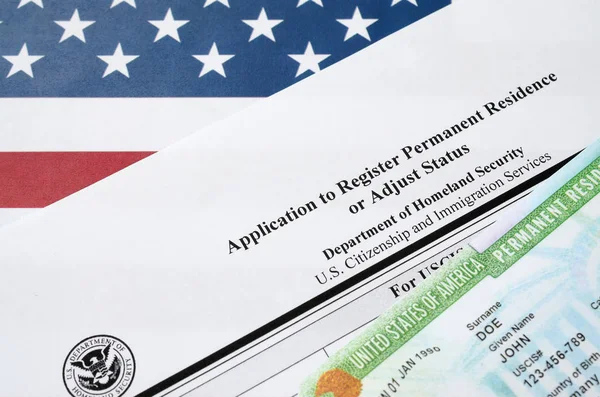 I-485 Aanvraag om permanent verblijf te registreren of aan te passen statusformulier en groene kaart van dv-loterij ligt op de vlag van de Verenigde Staten van het ministerie van Binnenlandse Veiligheid — Stockfoto