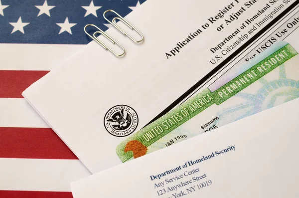 I-485 Application to register permanent residence or adjust status form and green card from dv-lottery lies on United States flag with envelope from Department of Homeland Security — Stock Photo, Image