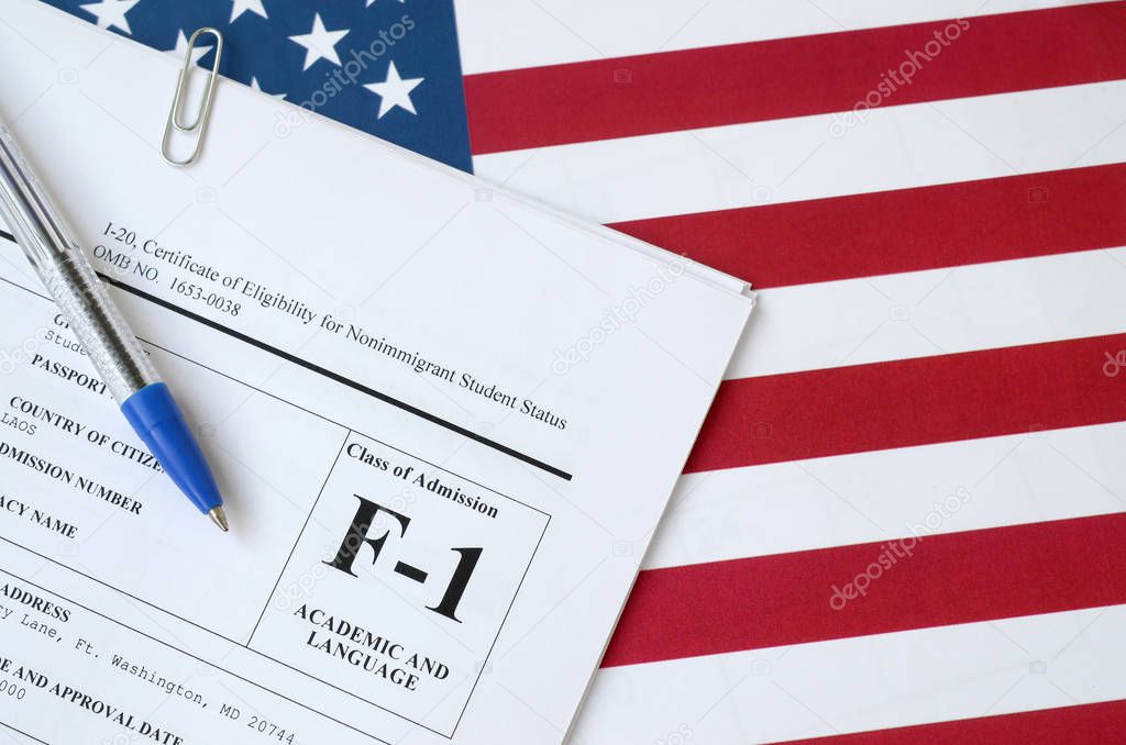 I-20 Certificate of eligibility for nonimmigrant student status blank form lies on United States flag with blue pen from Department of Homeland Security