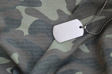 Kamuflaj üniformasında künyesi olan gümüşi askeri boncuklar.