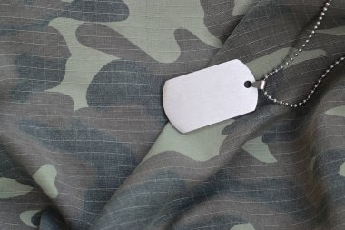 Silvery military beads with dog tag on camouflage fatigue uniform clipart