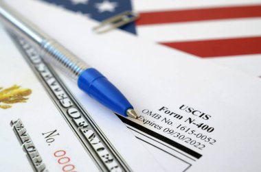 N-400 Application for Naturalization and Certificate of naturalization lies on United States flag with blue pen from Department of Homeland Security clipart