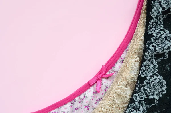 Bílé, černé a růžové dámské spodní prádlo s krajkou na růžovém pozadí s kopírovacím prostorem. Reklama na obchod krásné a pohodlné dámské spodní prádlo — Stock fotografie
