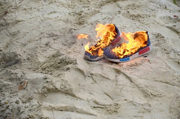 Brennende Turnschuhe oder Turnschuhe stehen am Sandstrand in Flammen. Sportler verbrannte. Körperliche Anstrengung beim Trainingskonzept — Stockfoto