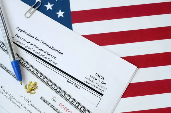 N-400 Žádost o naturalizaci a osvědčení o naturalizaci leží na vlajce Spojených států s modrým perem z Ministerstva vnitřní bezpečnosti — Stock fotografie