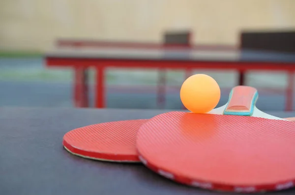 Schläger und Ball auf der Tischtennisplatte im Außensportplatz. Aktives Sport- und Bewegungskonzept — Stockfoto